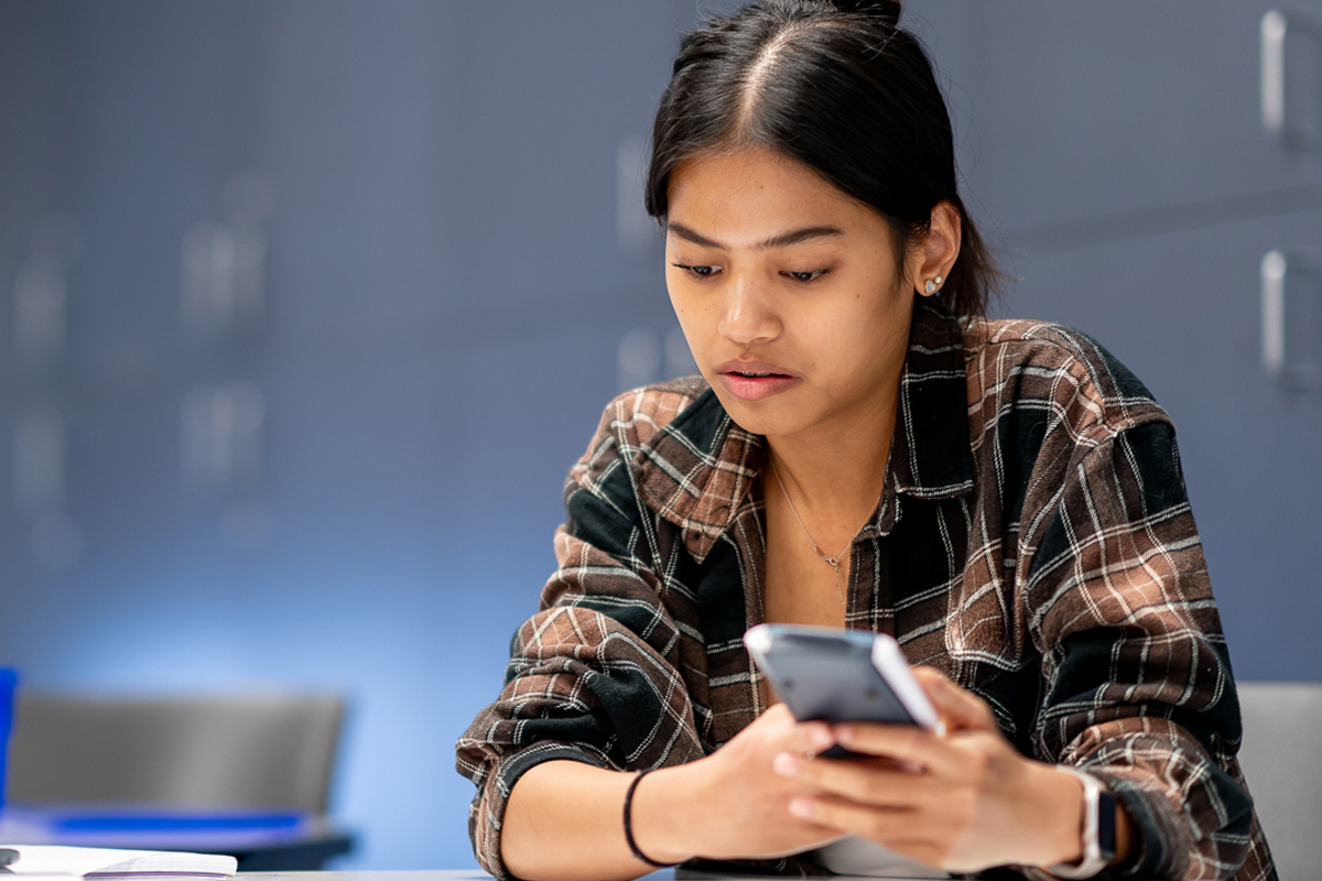 Youg woman sitting at desk holding a calculator.