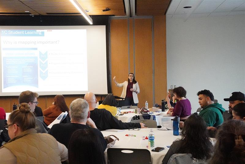 Dr. Snively-Martinez speaking to a group of faculty and staff while pointing at a projector screen slide