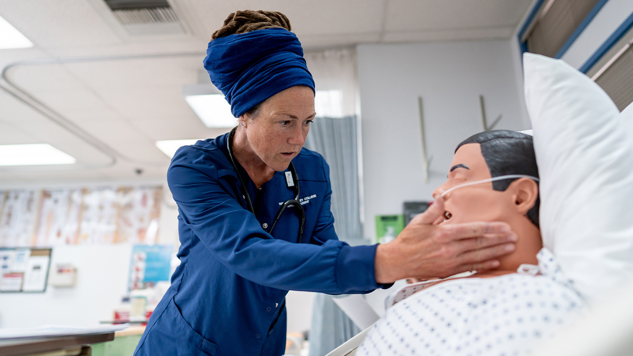 A WVC Omak nursing student checks the vitals on a manikin.