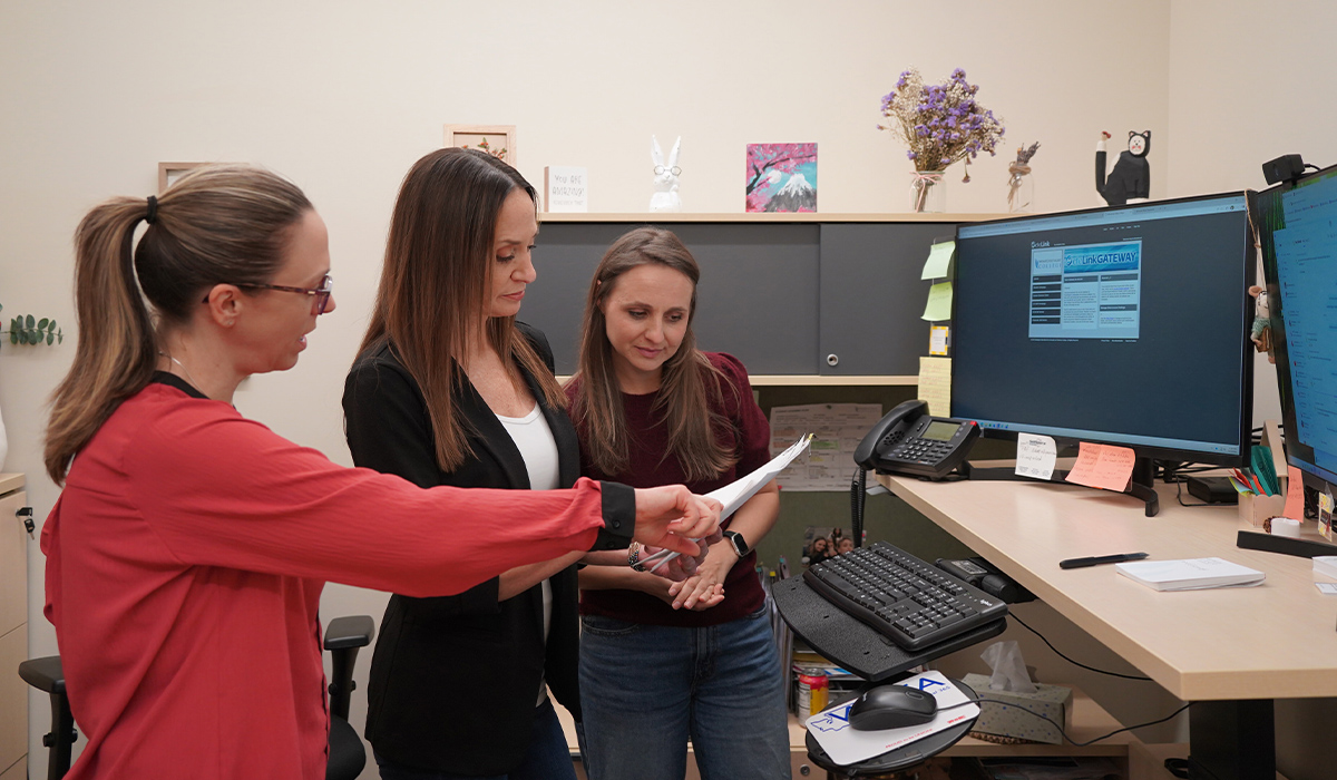 Three staff members in an office study a report.