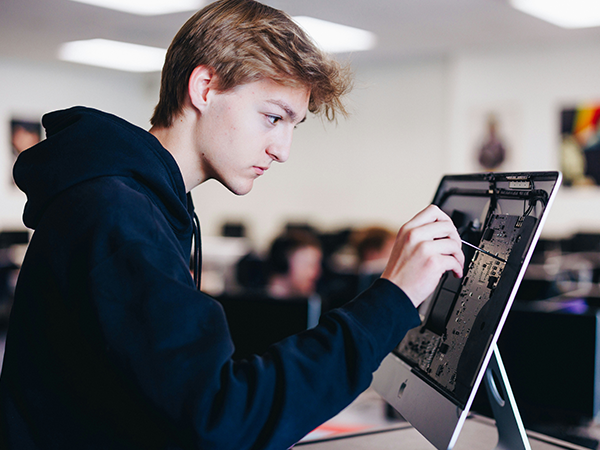 A student works on a computer's hard drive in a classroom.