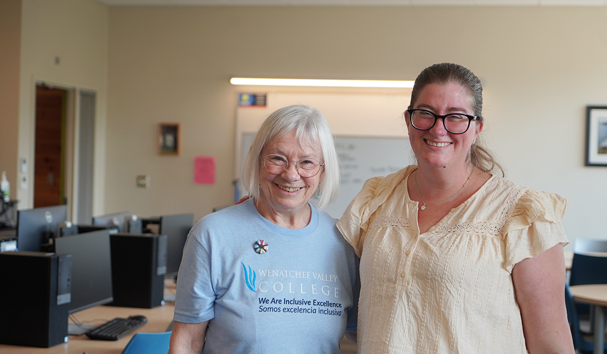 Two writing lab stand in the writing lab and smile at the camera.