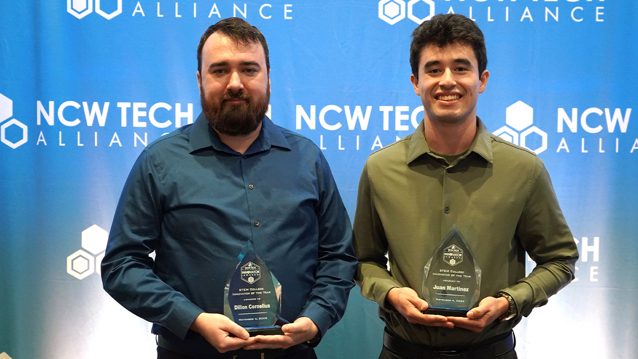 Two WVC Engineering students hold up their NCW Tech Alliance awards in front of a blue NCW Tech Alliance backdrop.