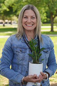 Portrait of Hillary Conner standing outside and holding a potted plant