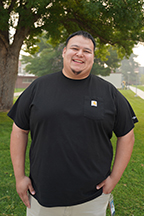 Portrait of Nelson Rojas standing outside on a lawn with the WVC Wenatchee campus in the background
