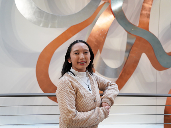 Portrait of Hailey Hopkins standing against a railing near a metal sculpture.