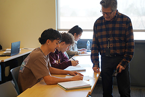 Professor Mike Choman helps a student with an assignment in class.