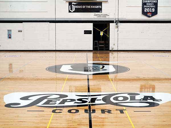 An image of the Smith Gym court with the Knights logo and Pepsi-Cola logo.